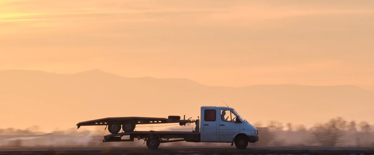 A tow truck vehicle with a car transporting carrier.